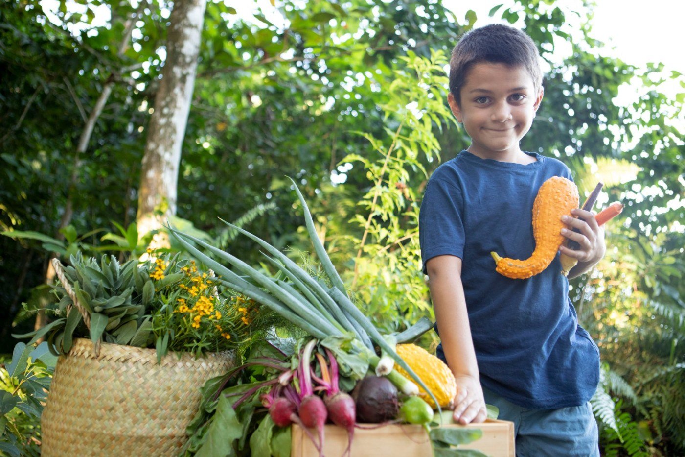 Ram beside the La Tierra sign with the day's harvest laid out on a bench